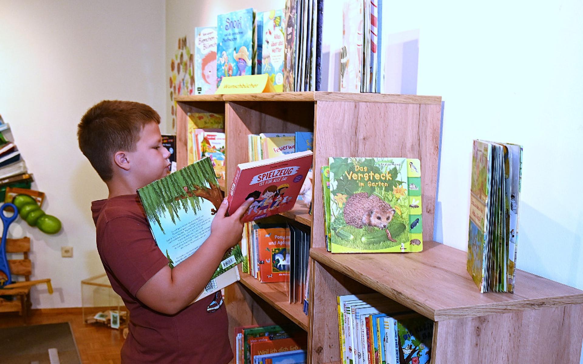 Bub mit Büchern vor einem Regal